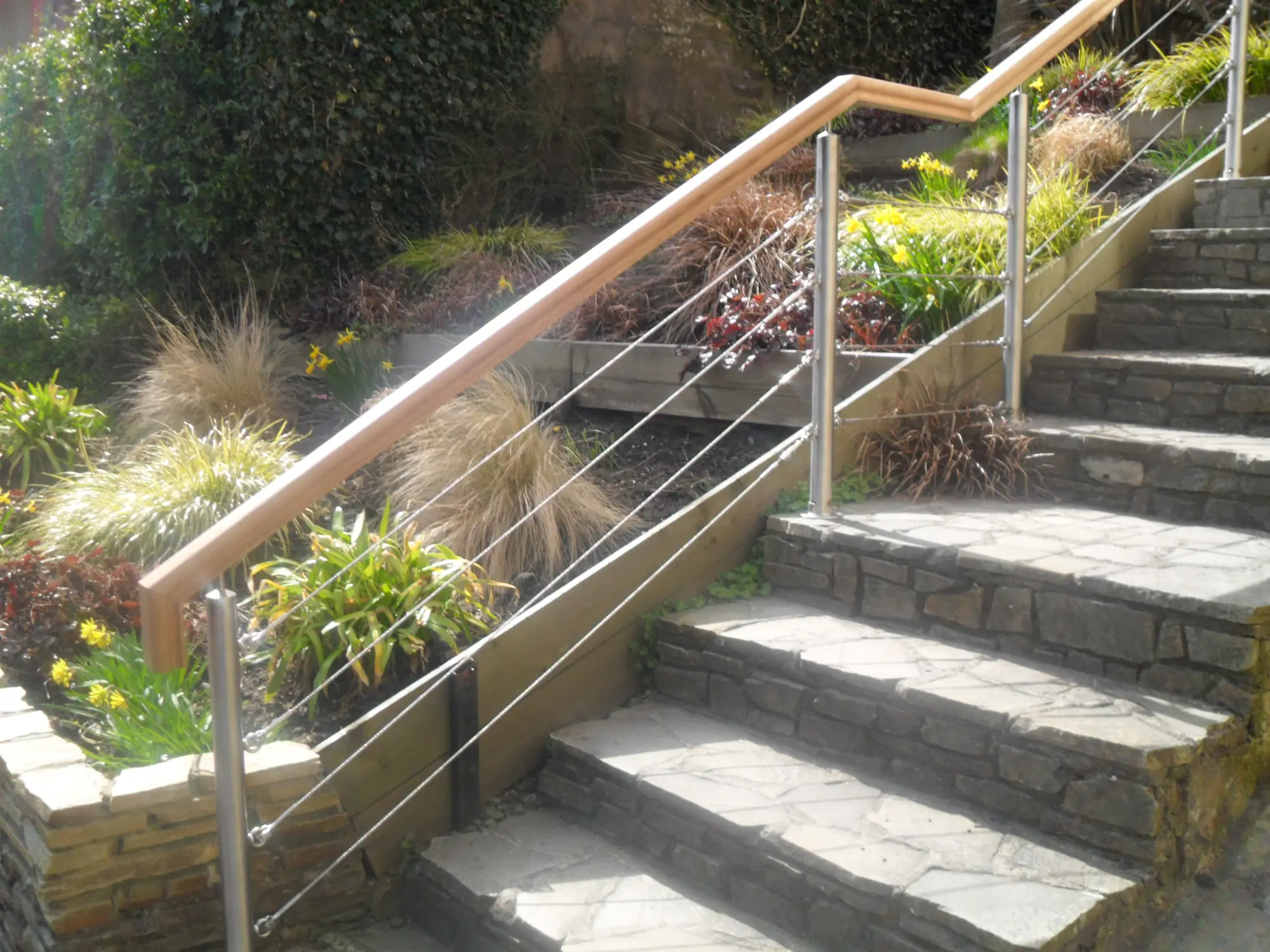 Stainless steel handrail with wire rope infill beside garden steps, made by Mac Engineering